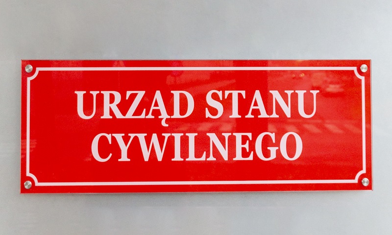 Czerwona, urzędowa tablica z napisem Urząd Stanu Cywilnego