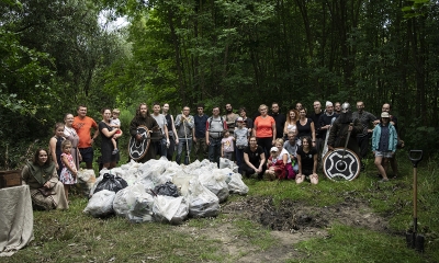Zbiorowe zdjęcie osób, które 25 lipca wysprzątały lasek wokół stawu "cegielnia", na tle drzew. W grupie osoby w strojach wikingów
