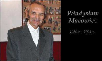 Starszy mężczyzna w garniturze i białej koszuli na tle ekspozycji historycznej. Z boku napis na czarnym tle - Władysław Macowicz 1930 - 2021