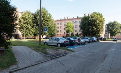 Rząd miejsc parkingowych, w głębi zielony teren, podwórko przy ul.Kochanowskiego - Paderewskiego